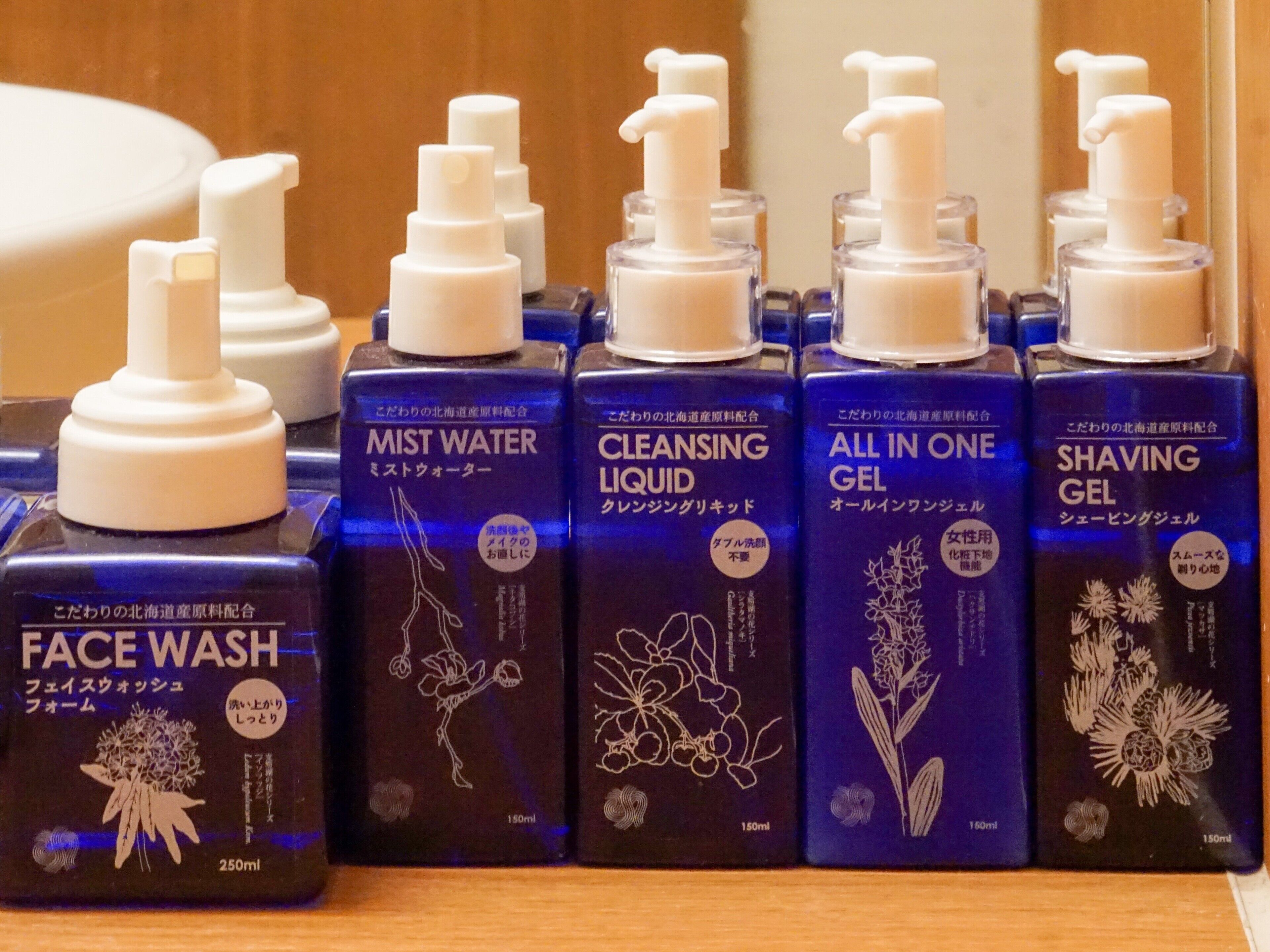 Una estantería con distintos productos de cuidado personal, como limpiador facial, loción limpiadora, gel todo en uno y gel de afeitar.