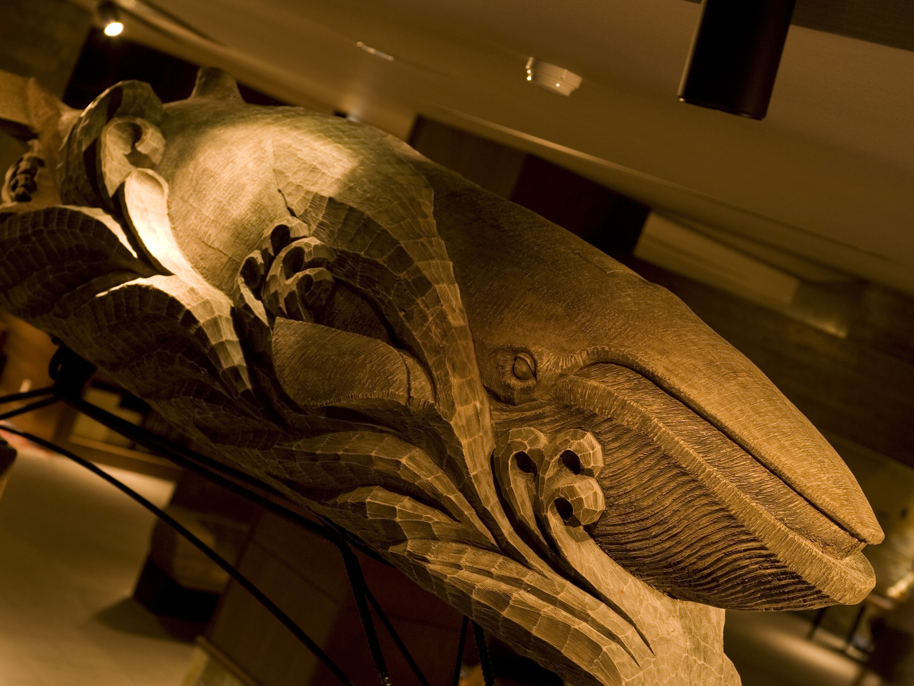 A detailed sculpture of a large animal, possibly a whale, with intricate carvings and a prominent eye.