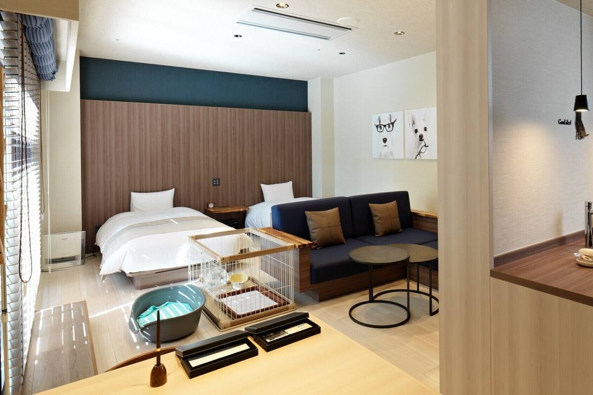 Una habitación de hotel con cama, sofá, mesita y kitchenette.