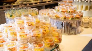 A buffet with various food items in clear containers, including seafood and garnishes.