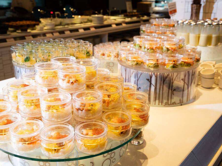 A buffet with various food items in clear containers, including seafood and garnishes.