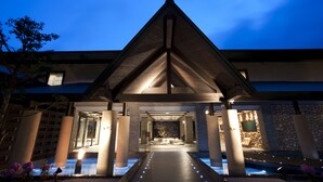 A modern building with a triangular roof, large pillars, and a pathway leading to a reception area.