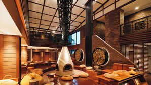 A spacious lounge area with a fireplace, comfortable seating, and a high ceiling with a skylight.