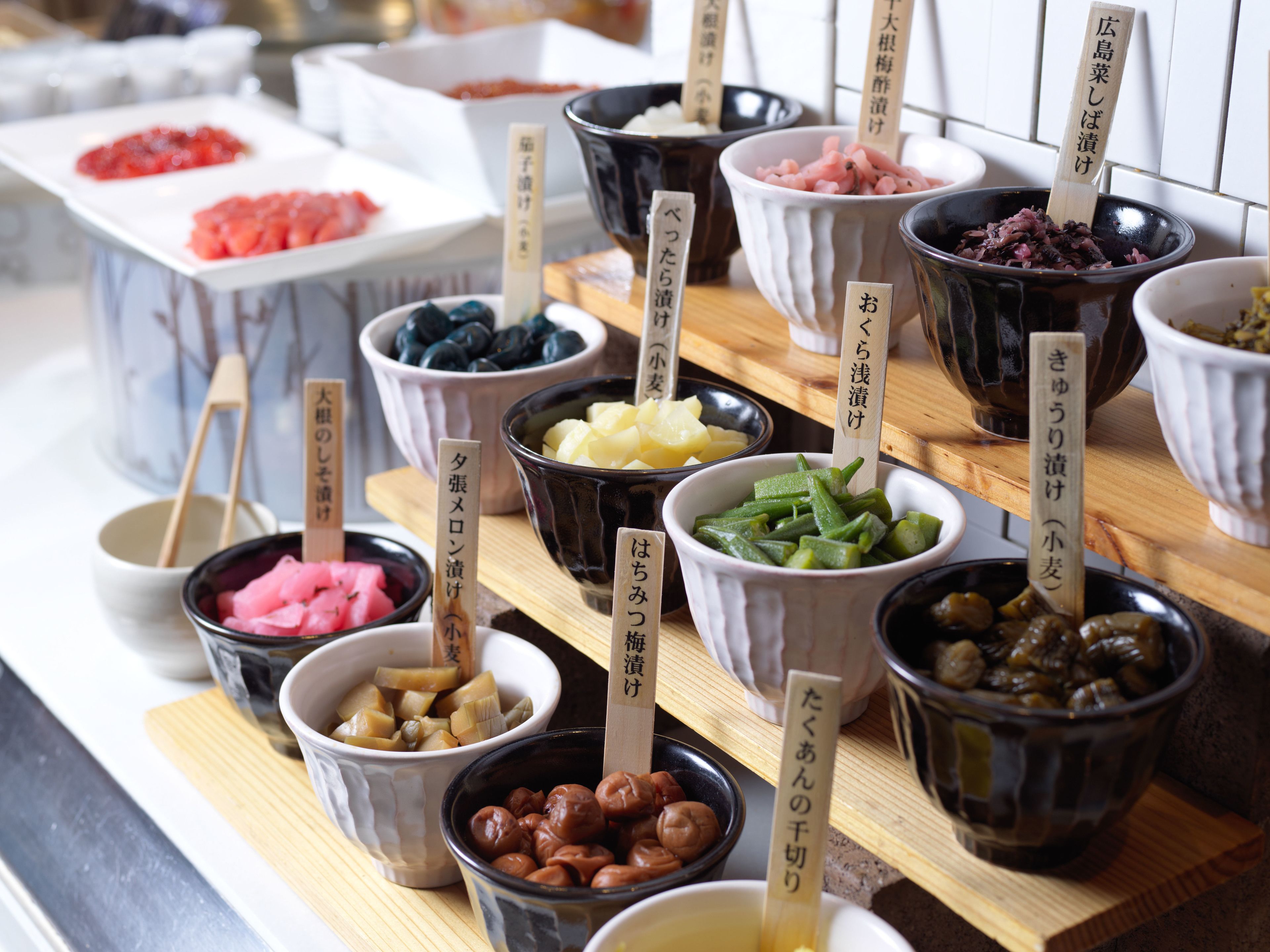 A variety of food items in bowls with labels, arranged on a wooden board.