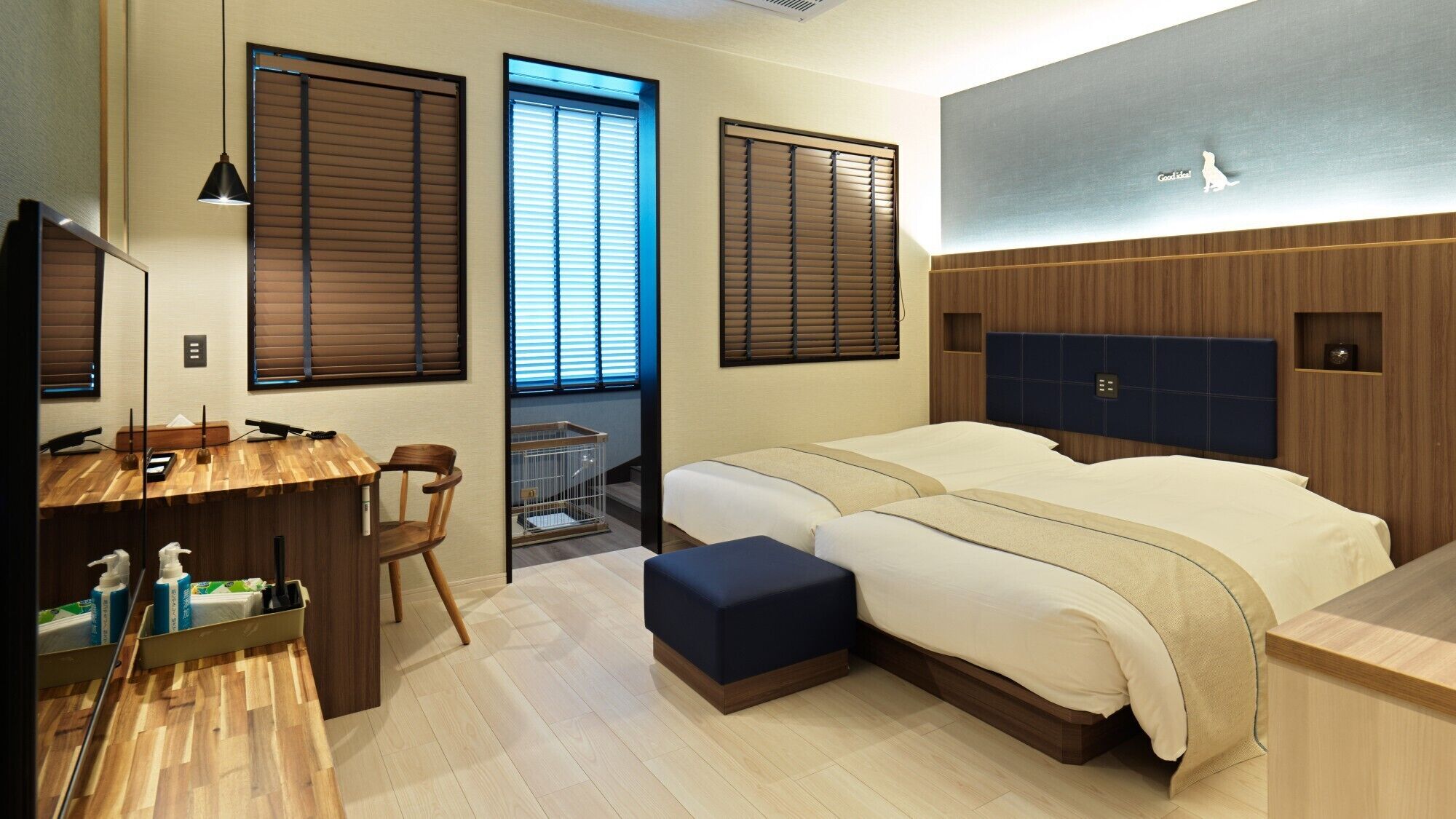Una habitación de hotel con un escritorio de madera, dos camas, un balcón pequeño y un espejo grande.