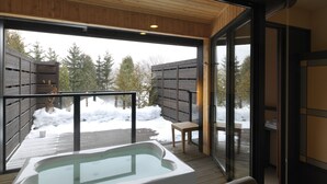A hot tub area with a view of a snowy landscape and a wooden deck.