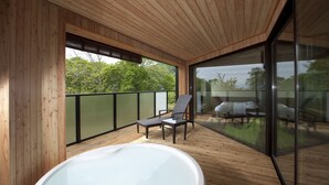 A wooden deck with a hot tub, two chairs, and a glass-enclosed balcony overlooking a green landscape.
