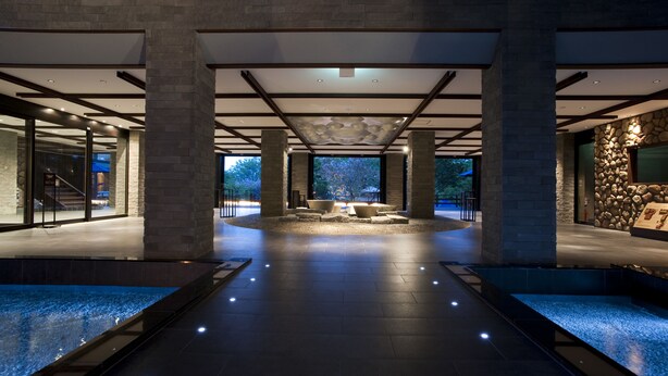 A spacious lobby with a central seating area, stone walls, and a view of the outdoors.
