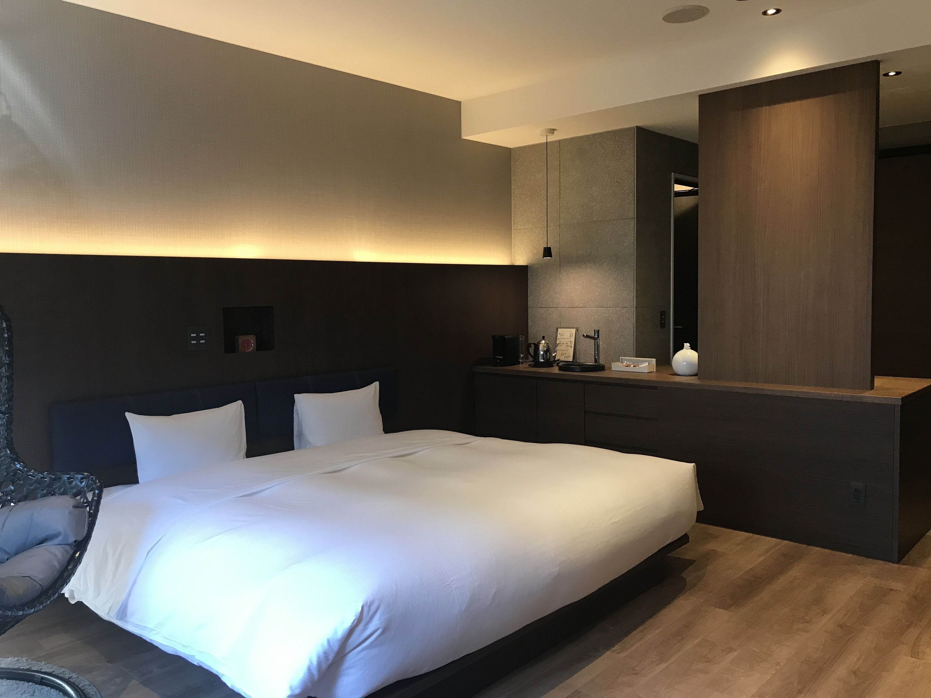 Et moderne hotelværelse med en stor seng, et natbord, et spejl og et lille siddeområde.