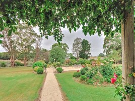 Um caminho no jardim leva a uma área de estar rodeada por vegetação exuberante e diversas plantas.