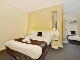 Quarto de hotel com uma cama grande, mesas de cabeceira, um espelho e um aparelho de ar condicionado.