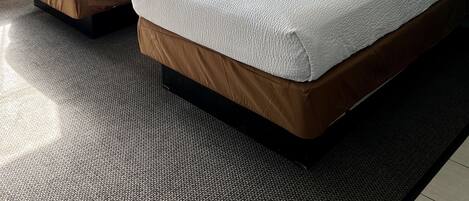 Une chambre d’hôtel avec deux lits, une grande fenêtre avec des rideaux et un sol recouvert de moquette.