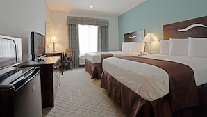 A hotel room with a bed, two bedside tables, a desk with a chair, a television, and a minibar.
