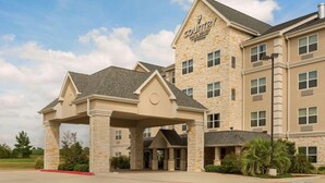 A Country Inn & Suites building with a stone facade, multiple windows, and a covered entrance. - Country Inn & Suites by Radisson, Texarkana, TX (Texarkana)