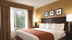 A hotel room with a large bed, a window with curtains, a nightstand with a lamp, and three framed pictures on the wall. - Country Inn & Suites by Radisson, Texarkana, TX (Texarkana)