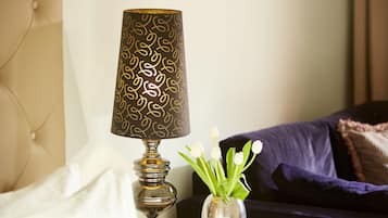 Eine Lampe mit gemusterten Lampenschirm und eine Vase mit weißen Blumen auf einem Tisch.