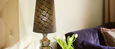 Een lamp met een patroonlampenkap en een vaas met witte bloemen op een tafel.