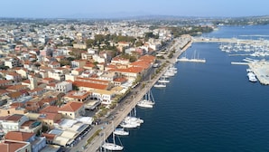 A coastal town with a marina filled with boats, a dense urban area with red-roofed buildings, and a clear view of the sea.