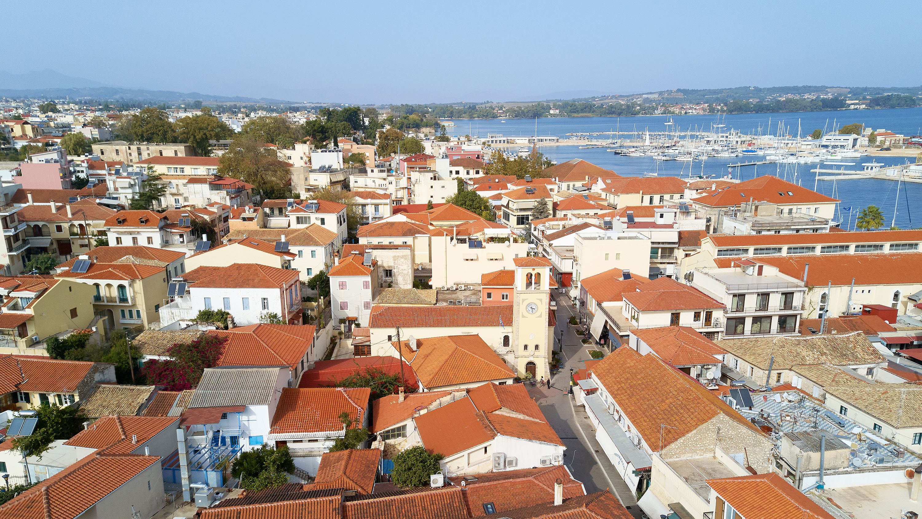 A coastal town with red-tiled rooftops, a marina, and a mix of residential and commercial buildings.