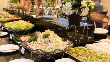 Ein reichhaltiges Buffet mit verschiedenen Speisen, darunter Salate und Meeresfrüchte, präsentiert auf einem Tisch mit einer Glastheke.