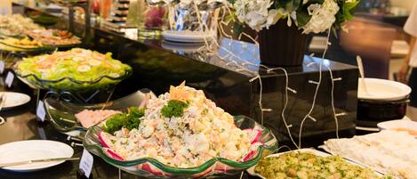 A buffet with various dishes, including salads and seafood, arranged on a table with a glass display case.