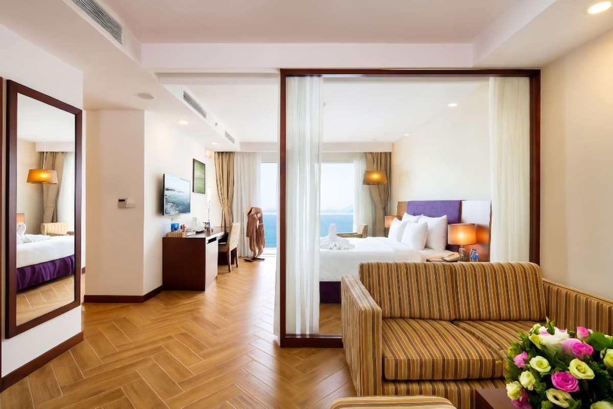 Habitación de hotel con cama, sofá, escritorio y un espejo grande.