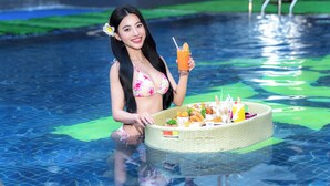 Una persona in piscina tiene in mano un drink e un cesto di cibo.