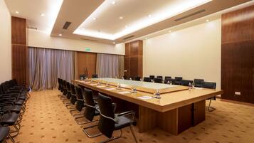 A conference room with a long table, black chairs, and a carpeted floor.