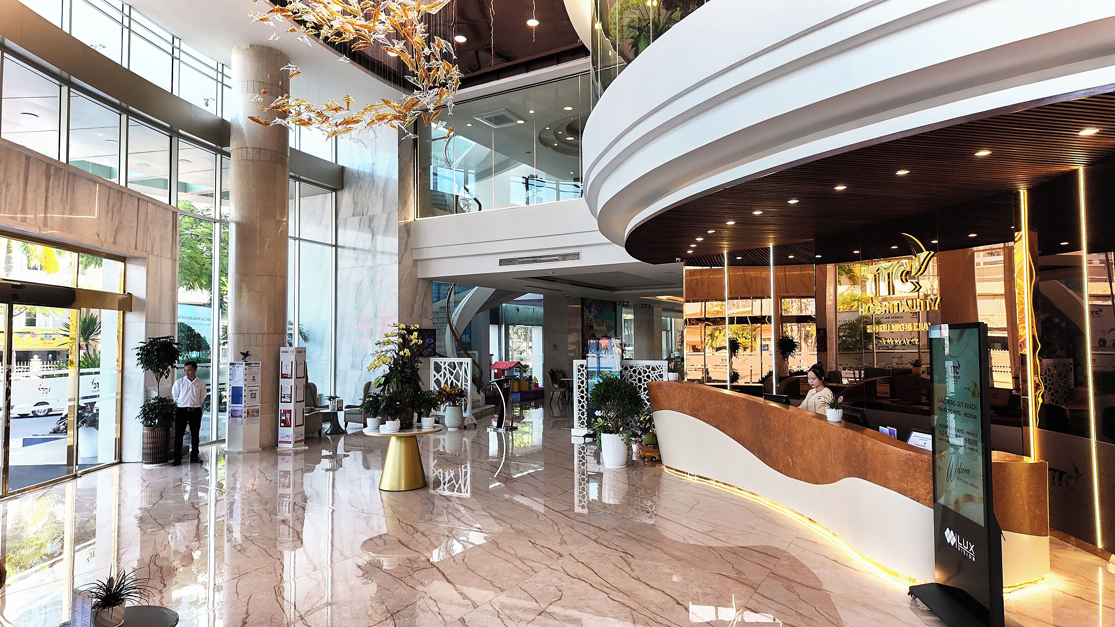 A spacious lobby with a high ceiling, large windows, and a reception desk.