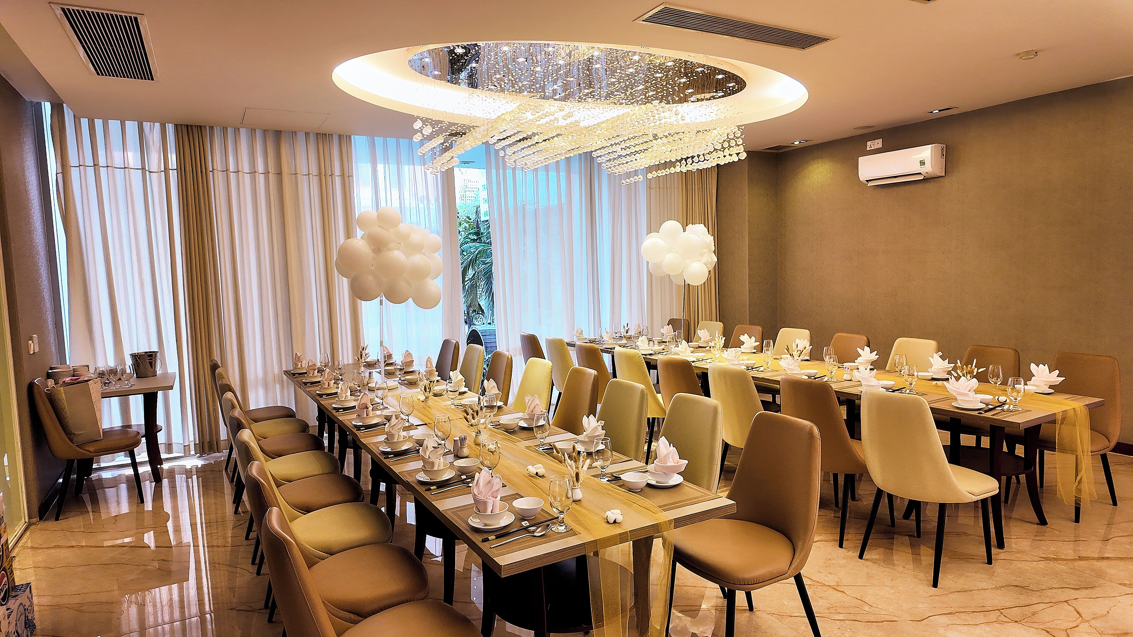Une salle à manger élégante, avec de longues tables, des chaises et un lustre.