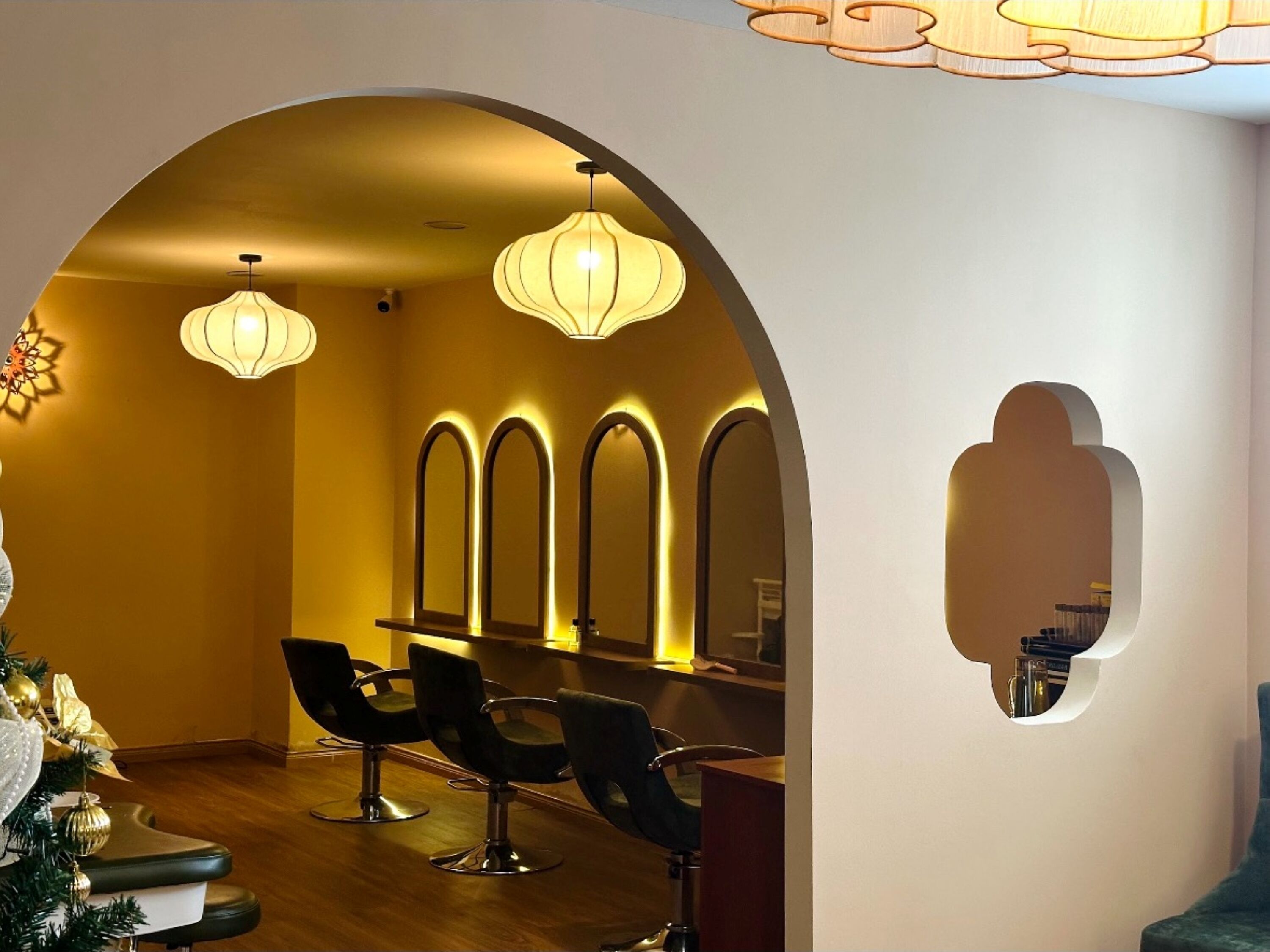 Un salon doté d’une arche incurvée, de plusieurs miroirs et de trois fauteuils.