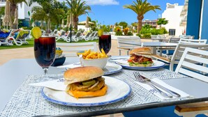 Uma mesa posta com um hambúrguer, batatas fritas, uma bebida e um sanduíche.