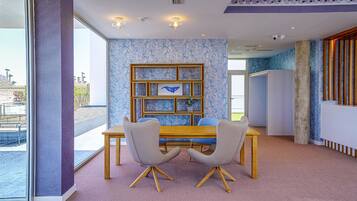 Un comedor moderno con una mesa de madera, dos sillas grises y una estantería con marco azul.