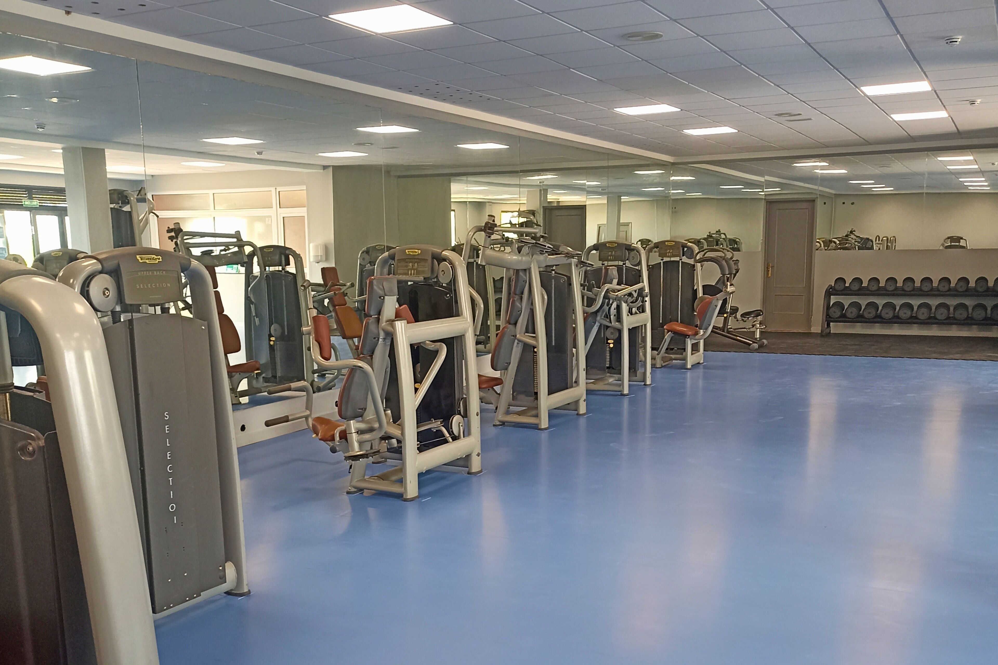 A gym with various exercise machines and a blue floor.