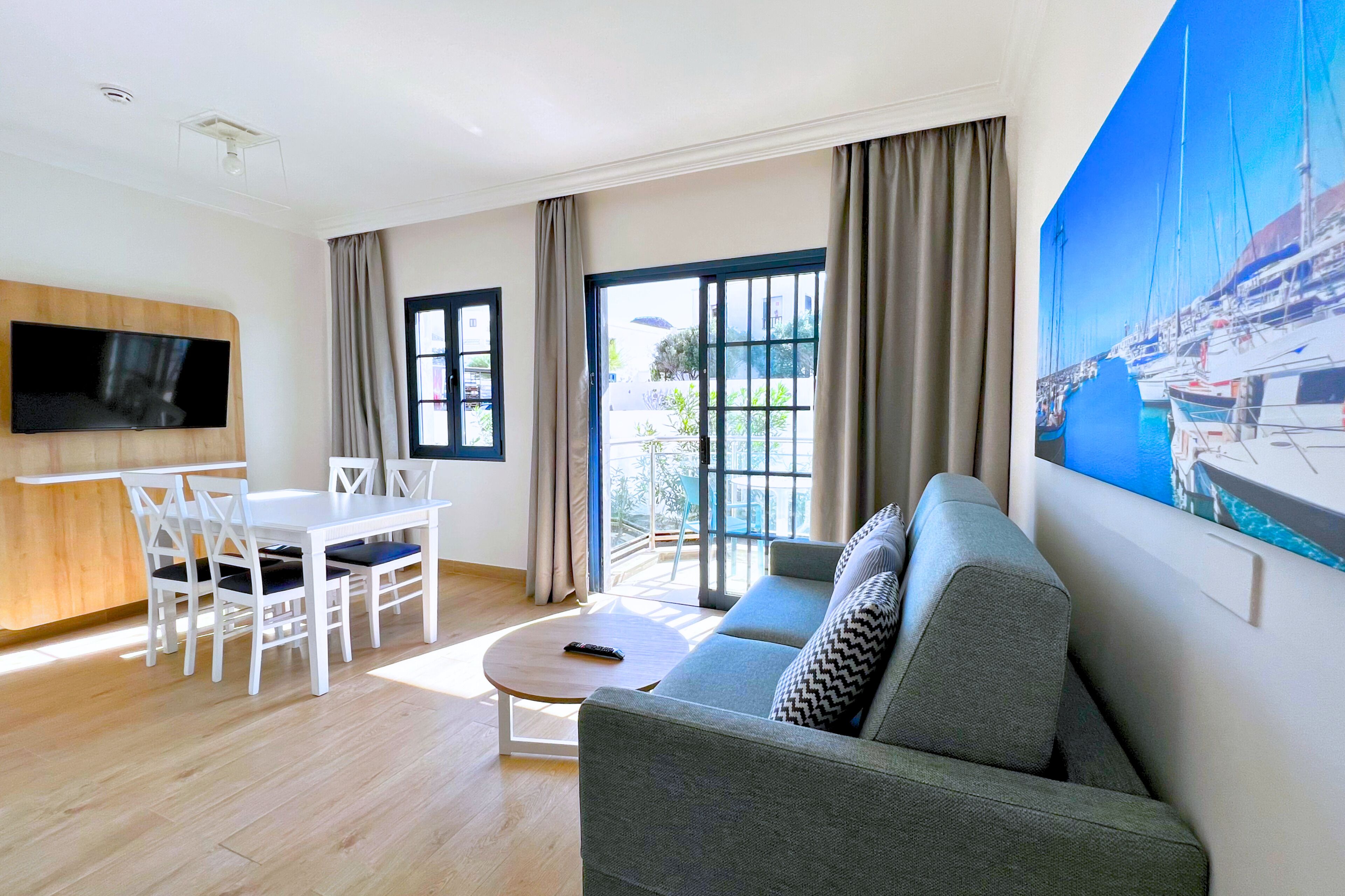 Una sala de estar moderna con un sofá, una mesa de comedor, sillas y un televisor.