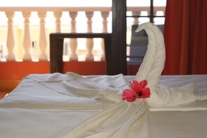 A neatly made bed with a towel shaped like a swan and a red hibiscus flower on it. - Grand Hotel Callao (Adeje)