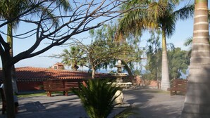 A courtyard with a fountain, palm trees, and a building with a tiled roof. - Grand Hotel Callao (Adeje)