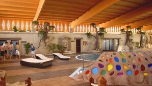 An indoor swimming pool area with lounge chairs and a colorful mural. - Grand Hotel Callao (Adeje)
