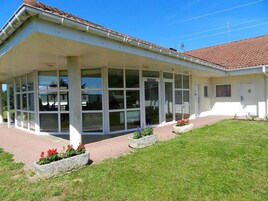 A building with a covered entrance, large windows, and a tiled roof.