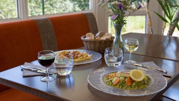 A dining table with plates of food, glasses of water and wine, and a vase of flowers. - The Originals Access, Hôtel Tulle (Tulle)