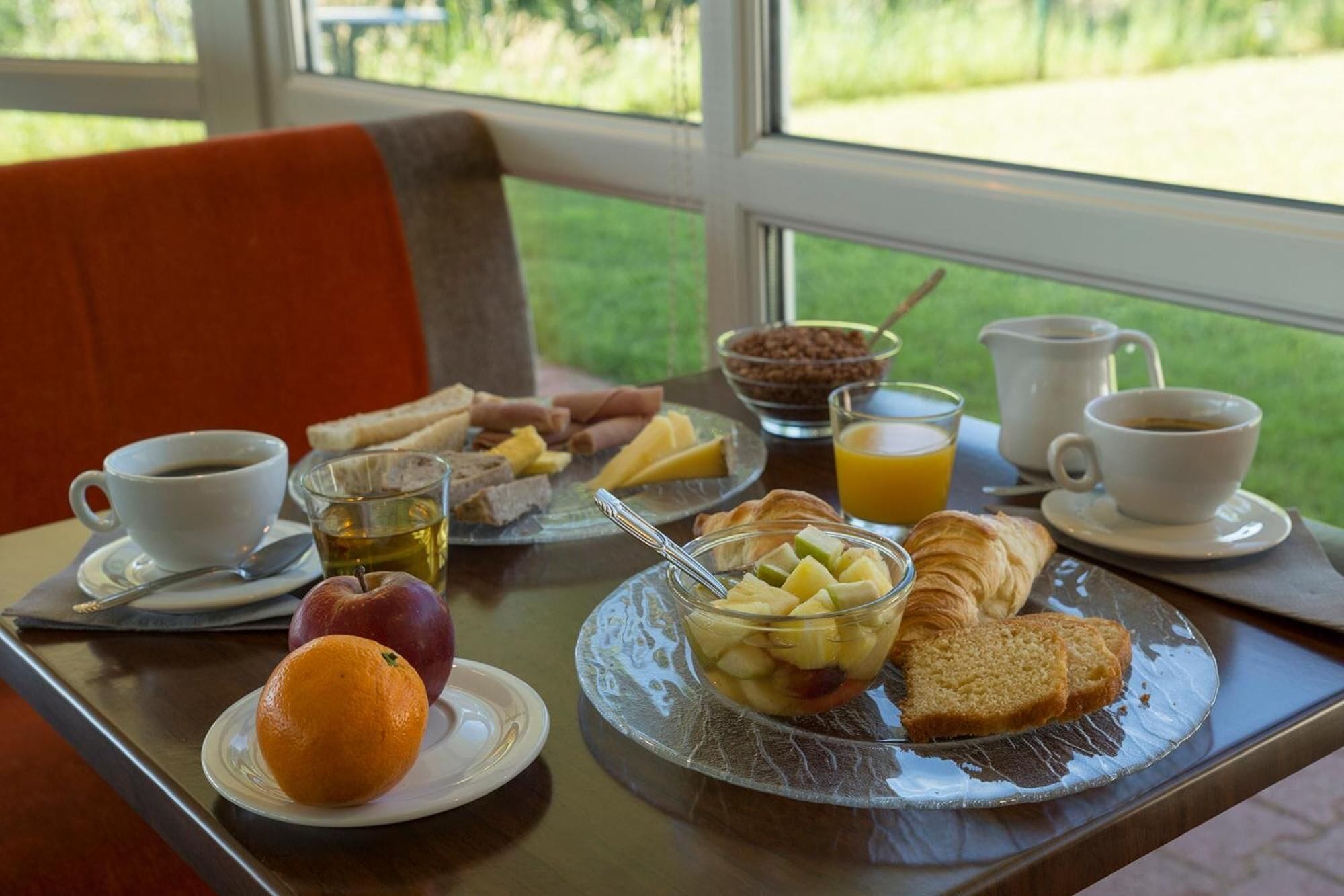 A breakfast table with various food items, a coffee cup, and a jug of orange juice.