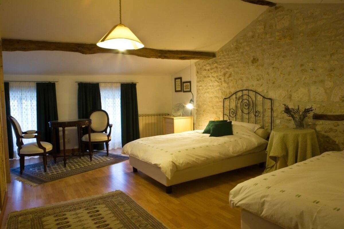 A bedroom with a bed, a chair, a table, and a lamp.