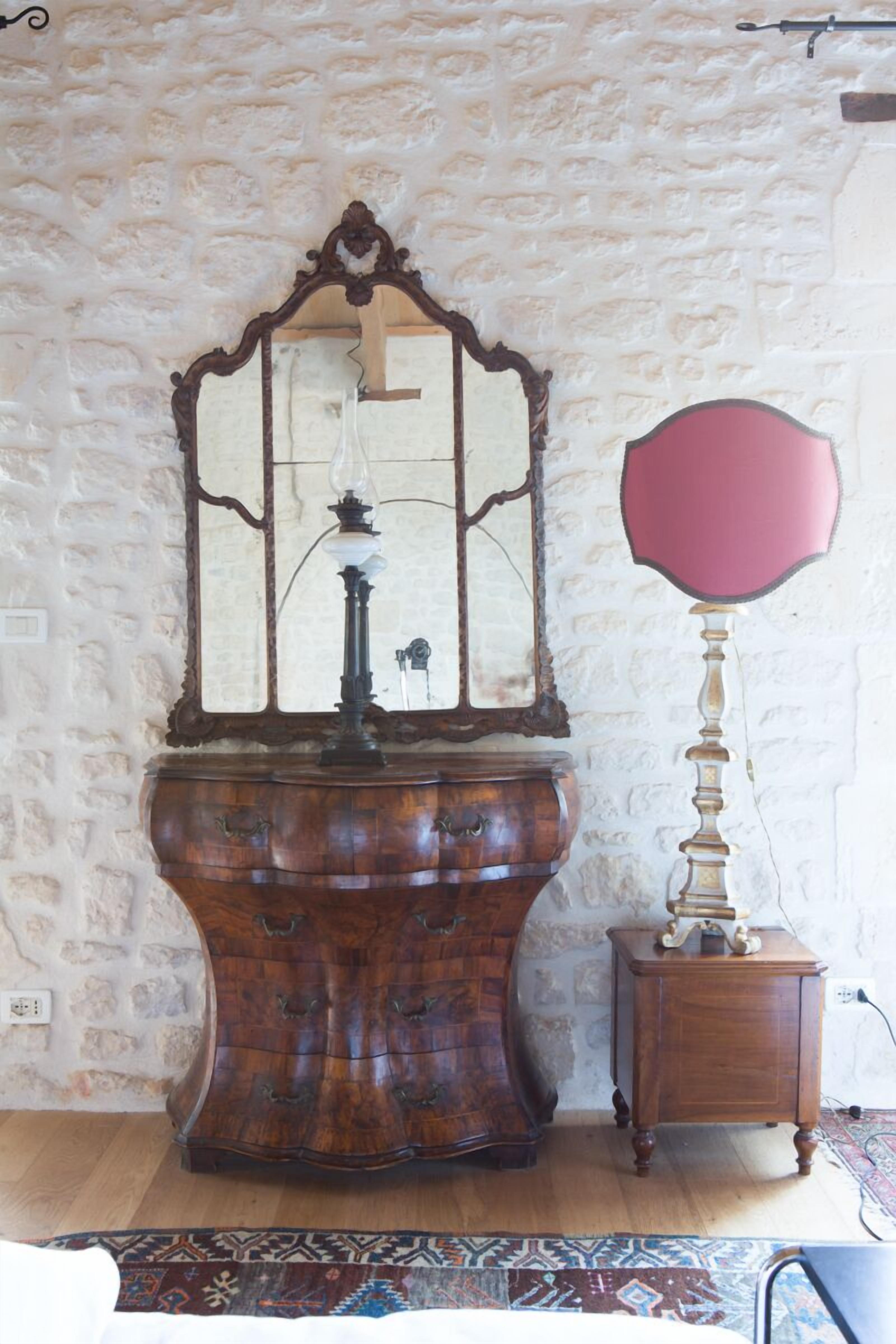A vintage wooden cabinet with a mirror and a small table beside it.