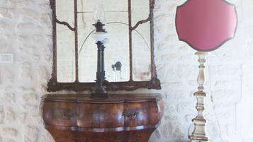 A vintage wooden cabinet with a mirror and a small table beside it.