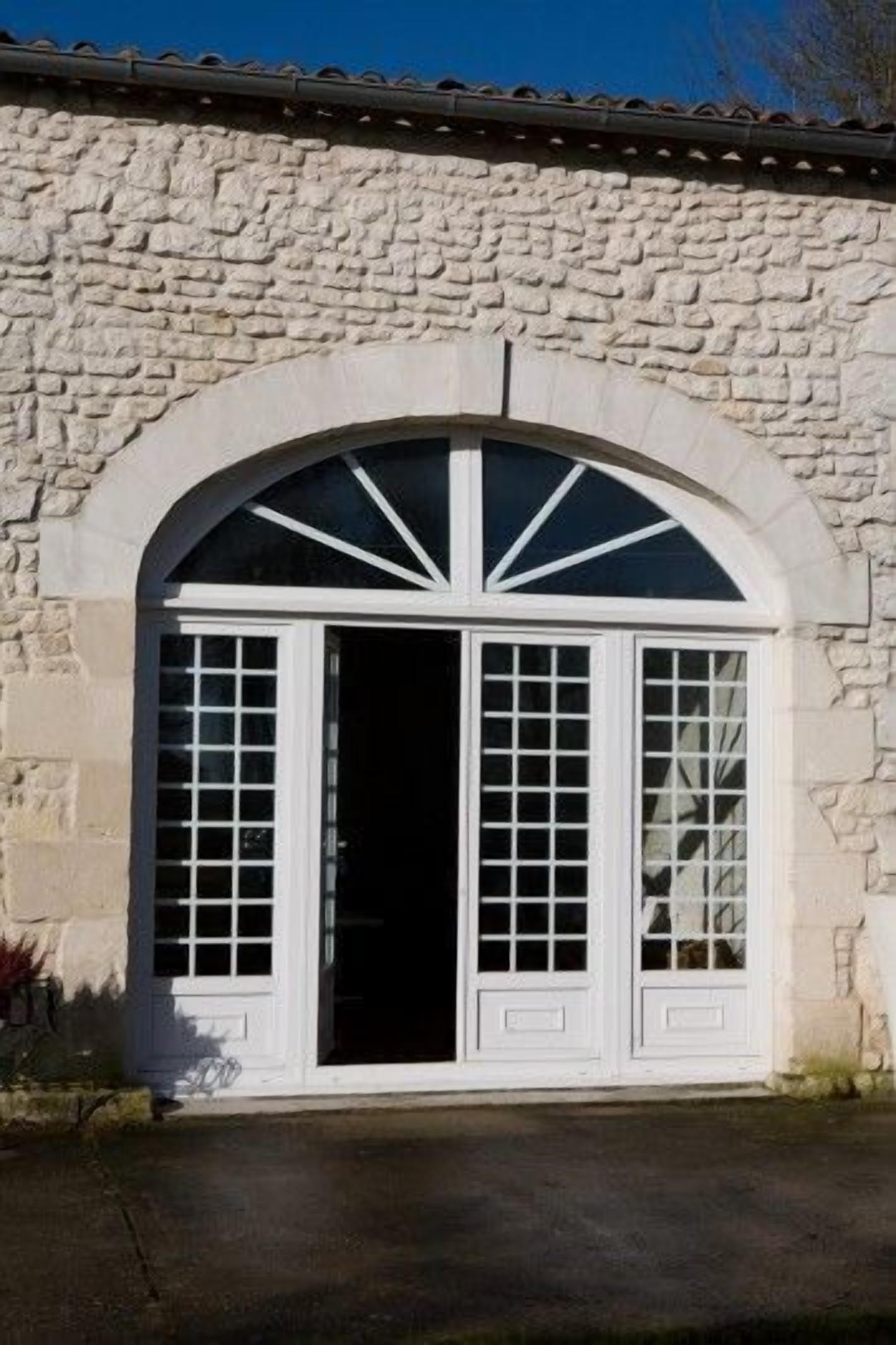 Un edificio de piedra con un amplio arco de entrada y dos ventanas simétricas.