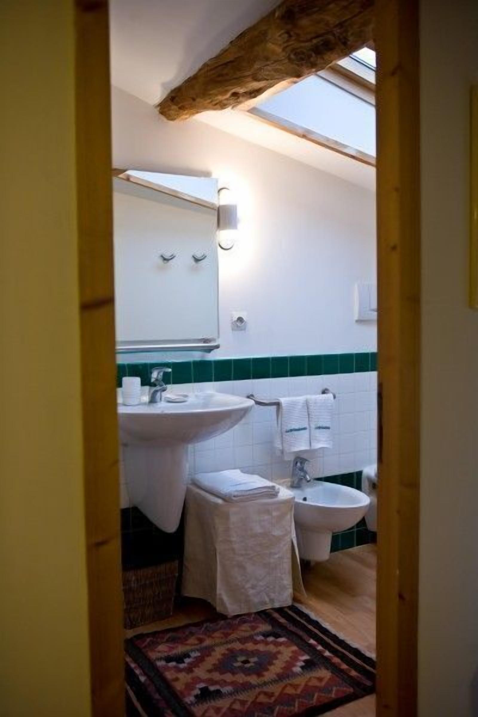 Ein schmales Badezimmer mit Oberlicht, Waschbecken, Bidet und kleiner Toilette.