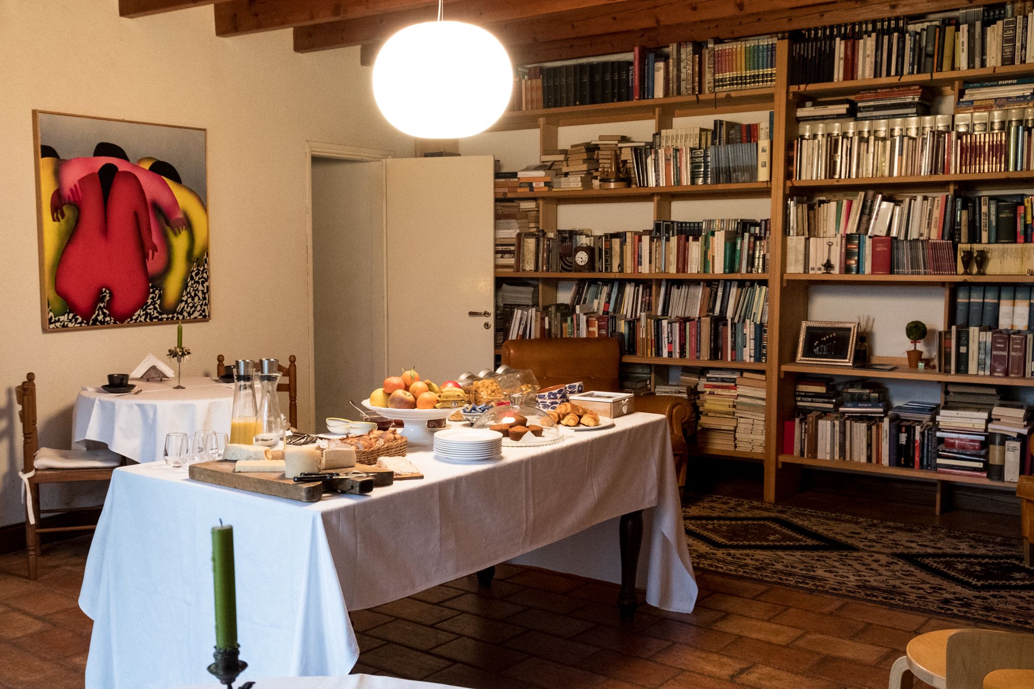 Een kamer met een ontbijt gedekte eettafel, omringd door boekenkasten vol boeken.