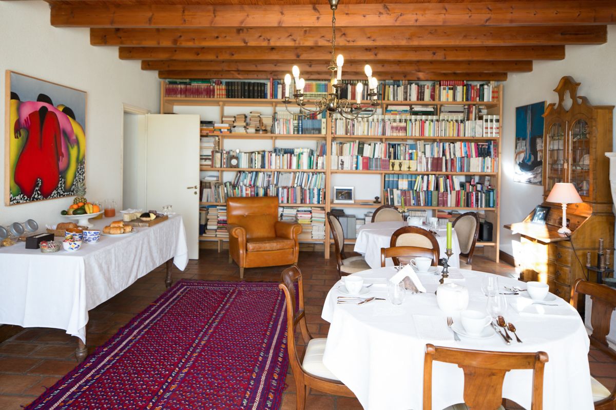 A dining area with a round table set for four, surrounded by bookshelves filled with books.