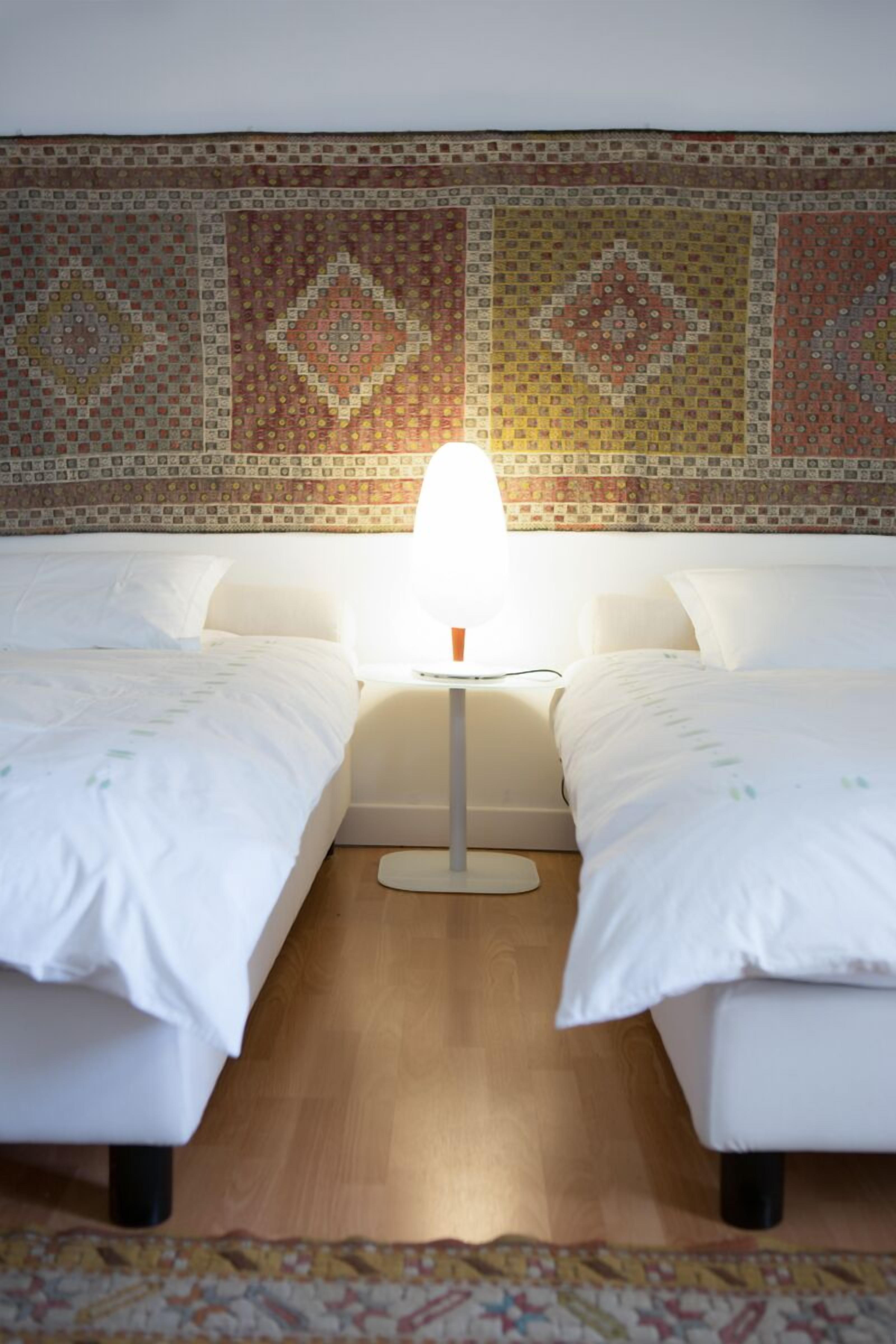 Een hotelkamer met twee bedden, een nachtkastje en een behang met een patroon.