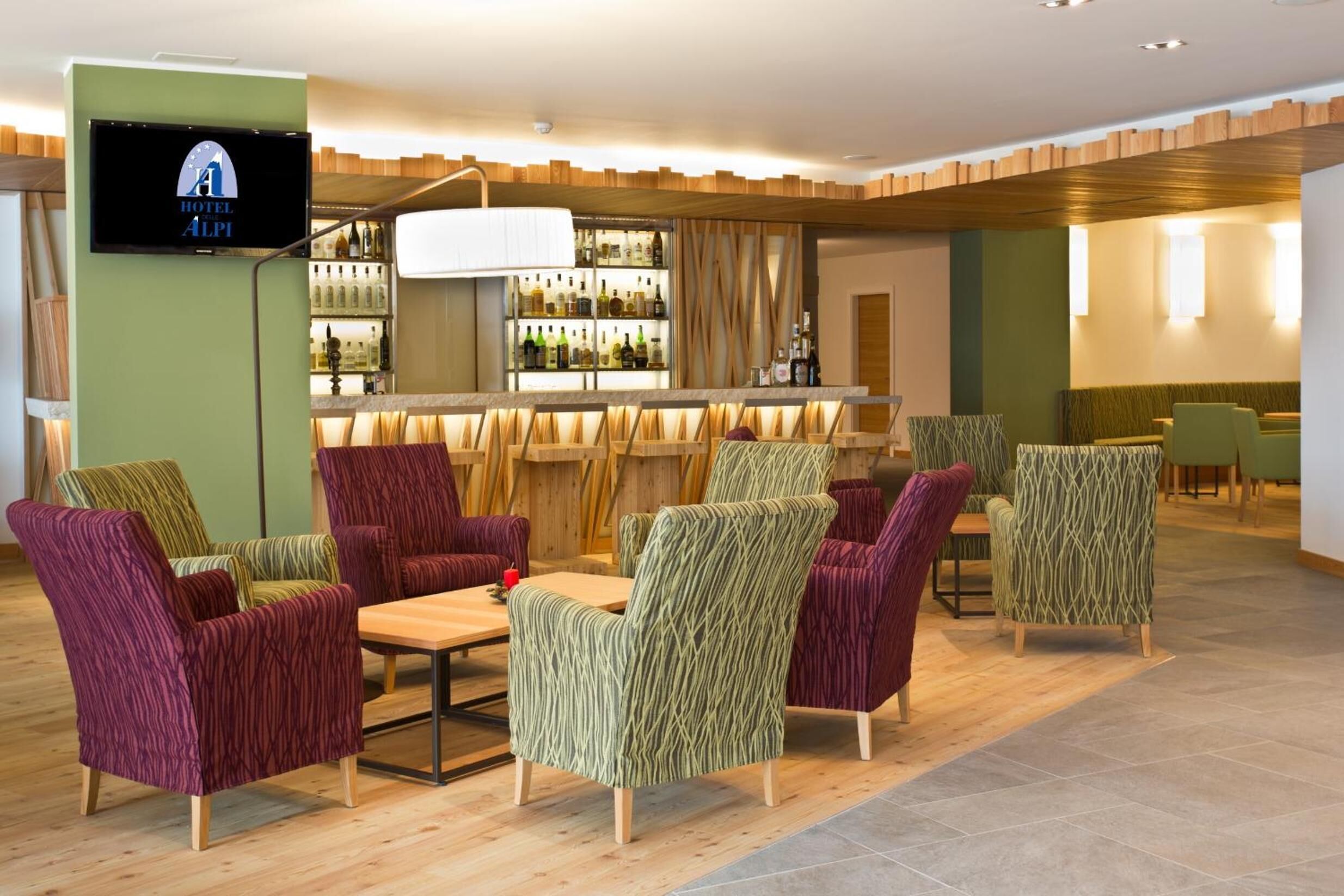 A hotel lobby with seating areas, a bar, and a television displaying the hotel name.